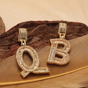 Pendenti con lettere Q e B in oro con zirconi cubici su sfondo artistico con piume