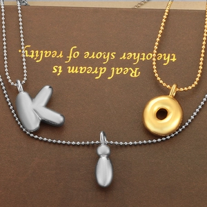 Détail du pendentif lettre K gonflé et motifs géométriques sur de fines chaînes à billes