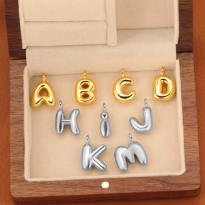 Détails macro de pendentifs alphabet ballon 3D en or et argent sur velours doux