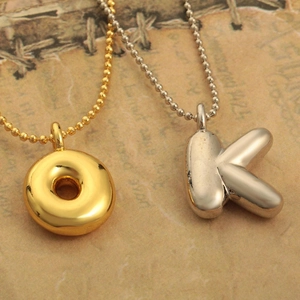 Colliers dorés et argentés avec pendentifs lettres et chaînes à billes sur papier vintage