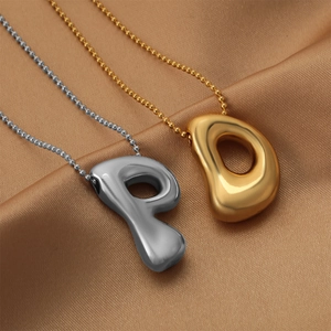 Detail of chubby fluid metal pendants in gold and silver on silk fabric background
