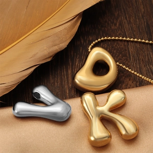 Golden and silver chubby letter pendants with glossy finish on elegant satin background