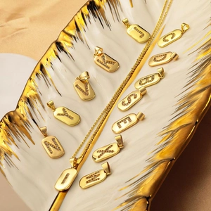 Gold letter pendants necklaces with micro-set zircons on an elegant ceramic tray