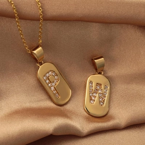 Golden capsule letter pendant with zircon P and W initials on a satin background