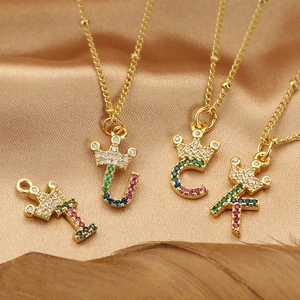 Collana con iniziali a corona dorata e zirconi colorati su sfondo di raso dorato