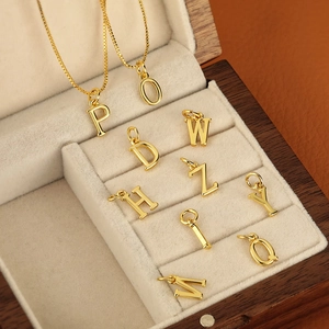 Ensemble de 26 pendentifs alphabet dorés polis présentés dans un écrin à bijoux
