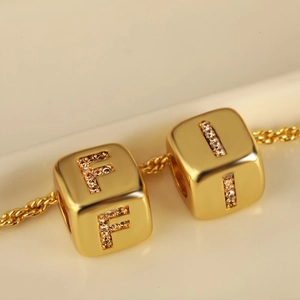 Collana minimalista in oro con pendenti a cubo lettere F e I e pietre di zircone