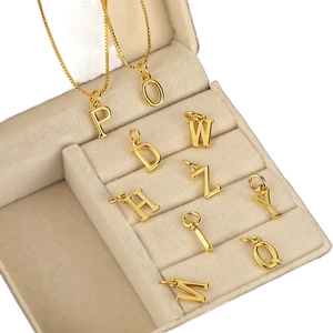 Colliers dorés avec pendentifs 26 lettres et chaîne box sur boîte à bijoux beige
