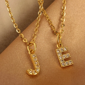 Gold plated copper necklace featuring dainty zircon paved initial pendants J and E