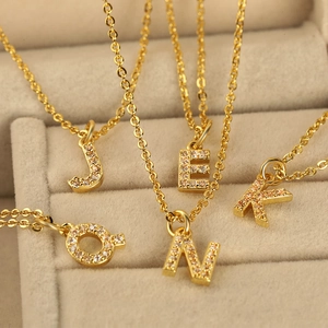 Gold plated copper initial necklaces with sparkling cubic zirconia on a velvet jewelry box