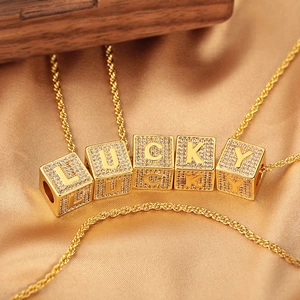 Collana dorata con lettere LUCKY e zirconi scintillanti su sfondo in seta e legno pregiato