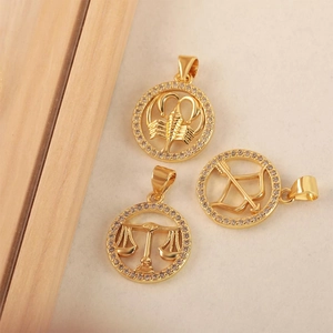 Gros plan de pendentifs zodiaque en plaqué or 18k avec zircons pour la Balance et le Scorpion