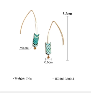 Detail view of gold arrow drop earrings with dimensions of 5.2cm length and 0.6cm width