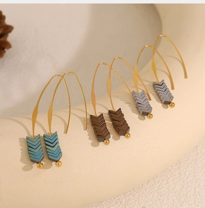 Detailed view of vintage V-shaped arrow earrings in green, brown, and grey matte finish