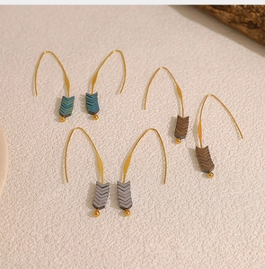 Detail of three pairs of minimalist V-shaped long hook earrings with colorful beads
