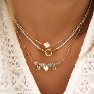 Detail van de drielaagse ketting met natuursteen en goudkleurige hartvormige hangers