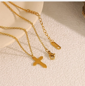 Detail of gold cross pendant necklace featuring lobster clasp and extension chain