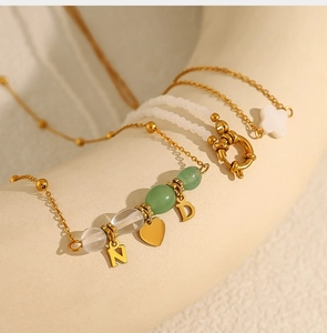 Detail van meerlaagse natuurstenen ketting met gouden hart hanger en klaver bedeltjes