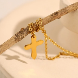 Gold stainless steel cross pendant necklace displayed on a natural wood branch