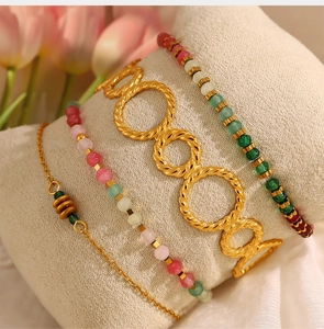 Detailed view of gold twisted rings and colorful beaded bracelets on fabric roll