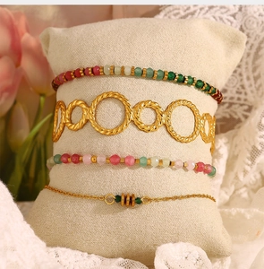 Detail of four-piece gold layered bracelet set with colorful beads on jewelry pillow
