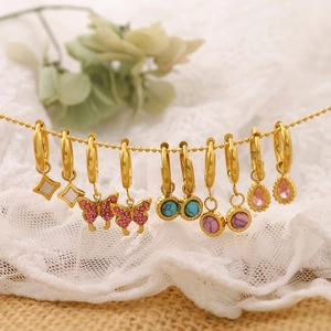 Macro detail of gold geometric hoop earrings with colorful natural stone charms and pearls