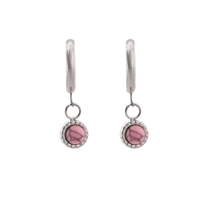 Detailed macro view of silver earrings featuring round pink natural stone pendants