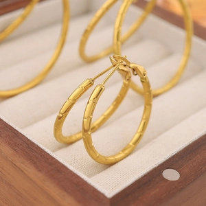 Close-up of golden bamboo texture hoop earrings in a wooden jewelry gift box