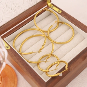 Three pairs of golden bamboo textured hoop earrings set in a wooden jewelry box