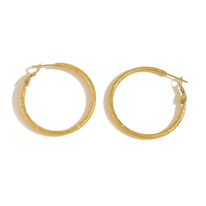 Close-up of golden bamboo-textured large hoop earrings with detailed metal grain finish