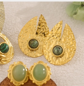 Macro detail of teardrop hammered gold earrings with green natural stones in retro style