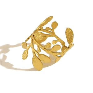Macro detail of leaf-shaped golden cuff bracelet with textured metallic hammer finish