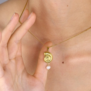 Collana con ciondolo a conchiglia dorata e perla bianca indossata da modella