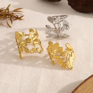 Minimalist leaf-shaped adjustable open rings in gold and silver finishes on fabric