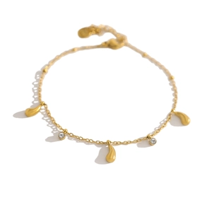 Detail van een gouden verstelbare armband met druppelvormige bedeltjes en zirkonia stenen
