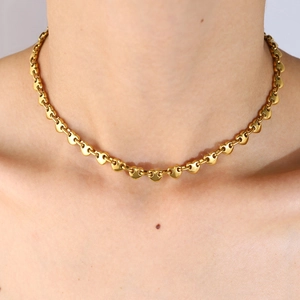 Primer plano de collar con eslabones de corazón 3D dorados en el cuello de una modelo