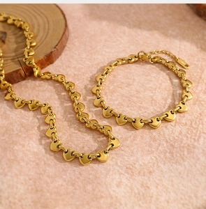 Detalle del conjunto de collar y pulsera de eslabones de corazón en oro pulido