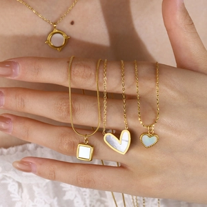 Detail view of 18K gold plated necklaces featuring white shell heart and geometric pendants