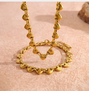 Primer plano de un collar dorado con eslabones pulidos en forma de corazón y cierre de mosquetón