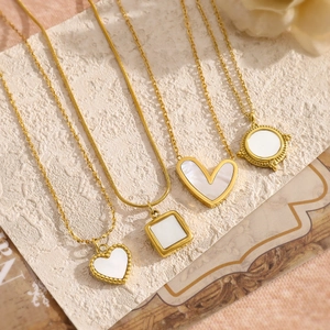 Four-piece gold necklace set with heart and geometric shell pendants on textured background