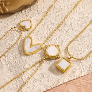 Detailed shot of four gold necklaces with white shell heart and geometric pendants