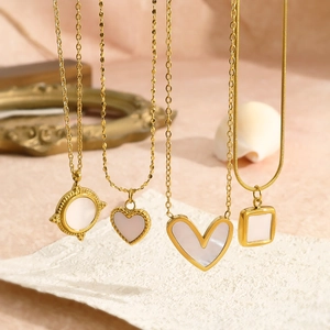 Detail view of gold necklaces with white mother of pearl heart and geometric pendants