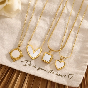 Detail of gold shell necklaces in round and heart shapes on a cream fabric gift bag
