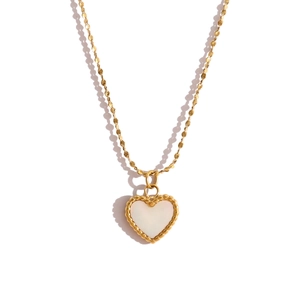Close-up of golden necklace with heart-shaped white shell pendant and beaded edge detail