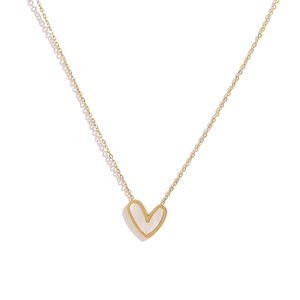 Macro shot of gold asymmetric heart pendant featuring white mother-of-pearl inlay