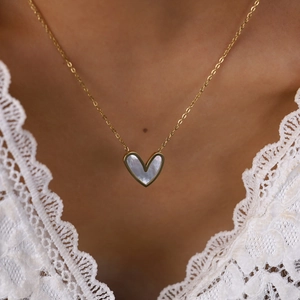 Elegant gold heart necklace with white mother-of-pearl inlay worn on model closeup