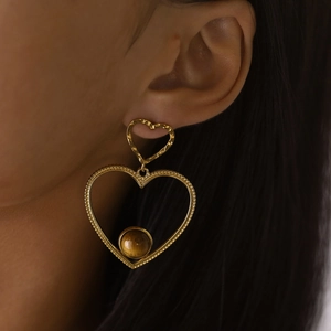 Dettaglio di orecchini a doppio cuore in oro 18K con texture vintage e occhio di tigre