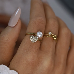 Detailed macro of 18K gold ring with white pearl and sparkling heart-shaped diamond inlay