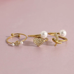 Detailed view of three 18K gold-plated rings with pearls, heart shapes and star designs
