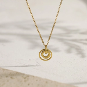 Detalle macro de collar dorado con colgante de anillo martillado irregular y cadena fina